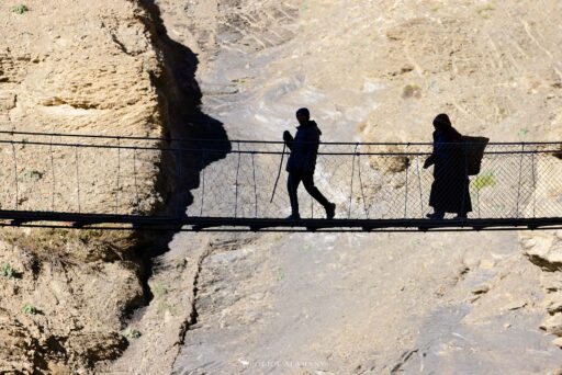 Dolpo silhouettes of people crossing a hanging bridge